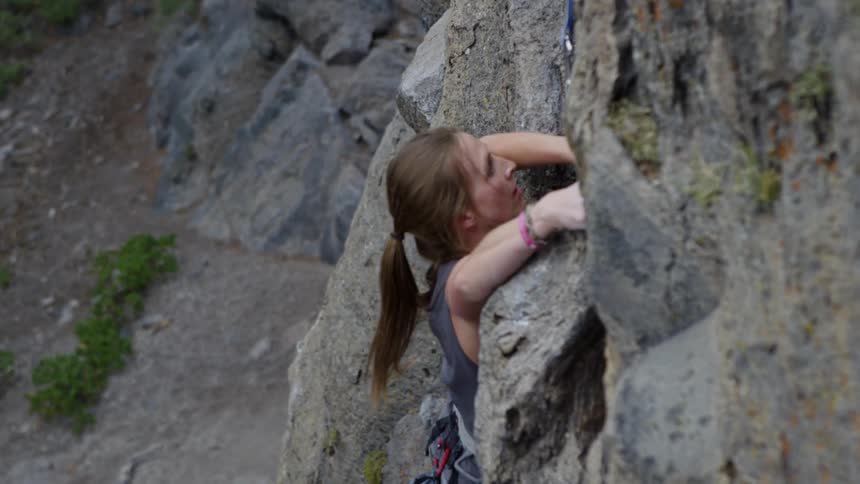 Woman rock climbing on a vertical cliff