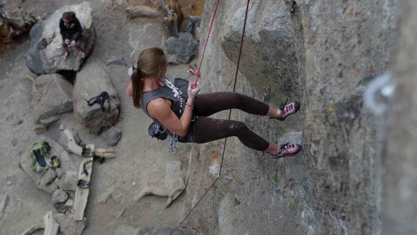 A woman is climbing down the cliff on a harness
