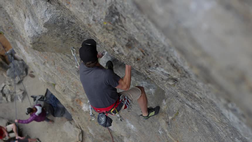Man wearing a safety harness does some rock climbing