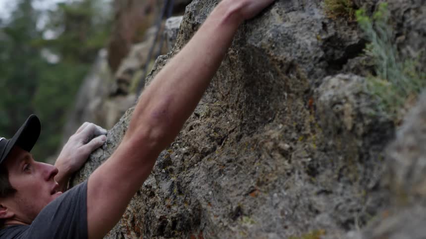 A man blows the chalk on his hand as he rock climbs