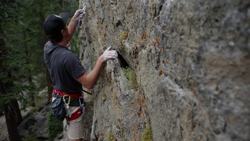 Man rock climbing a vertical wall on the mountains