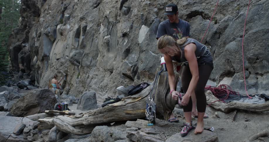 Two women a man and a dog near a cliff with rock climbing equipment