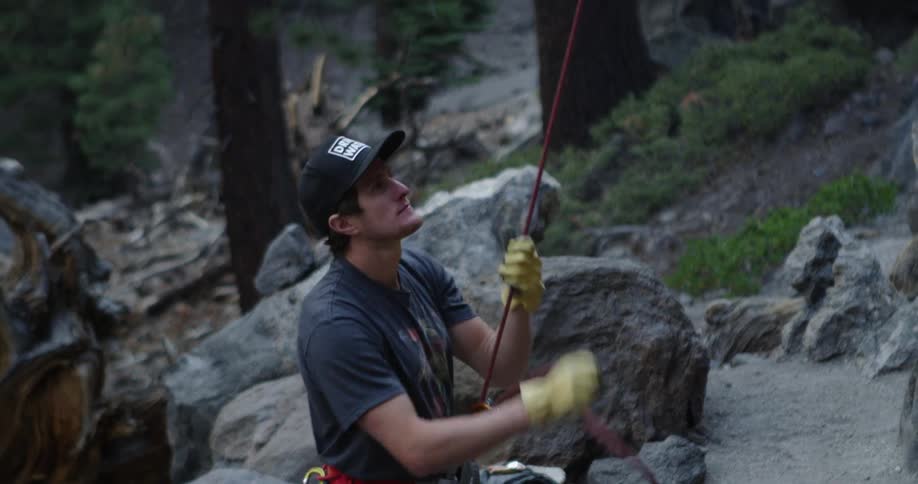 A rock climber is pulling the rope on his harness