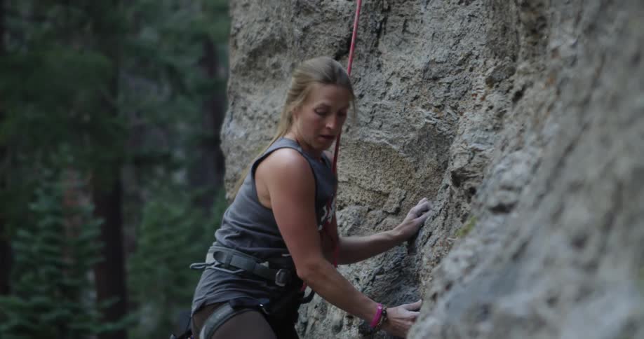A woman is rock climbing up a steep cliff