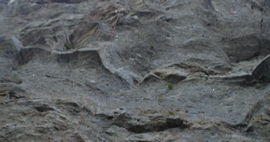 Man tightens climbing rope for rock climber on cliff above