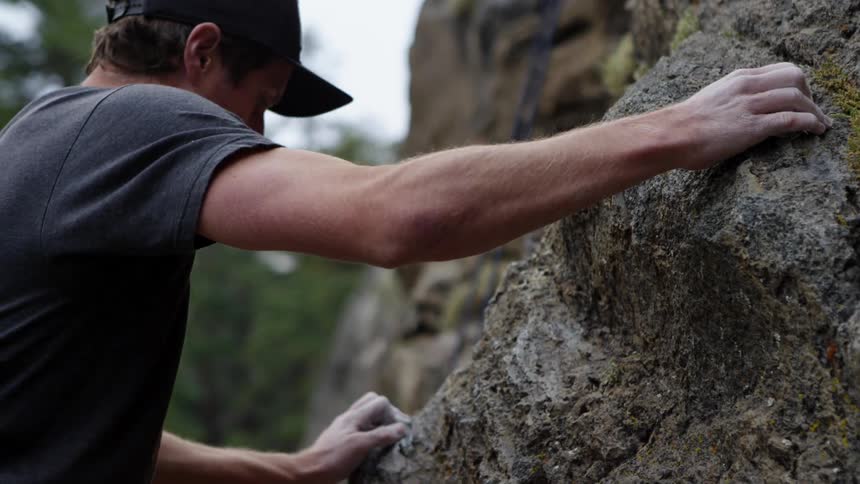 A white male climbs a steep rocky mountain