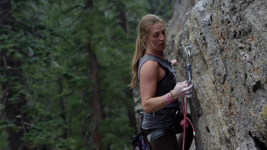 A woman is climbing a mountain in a forest area