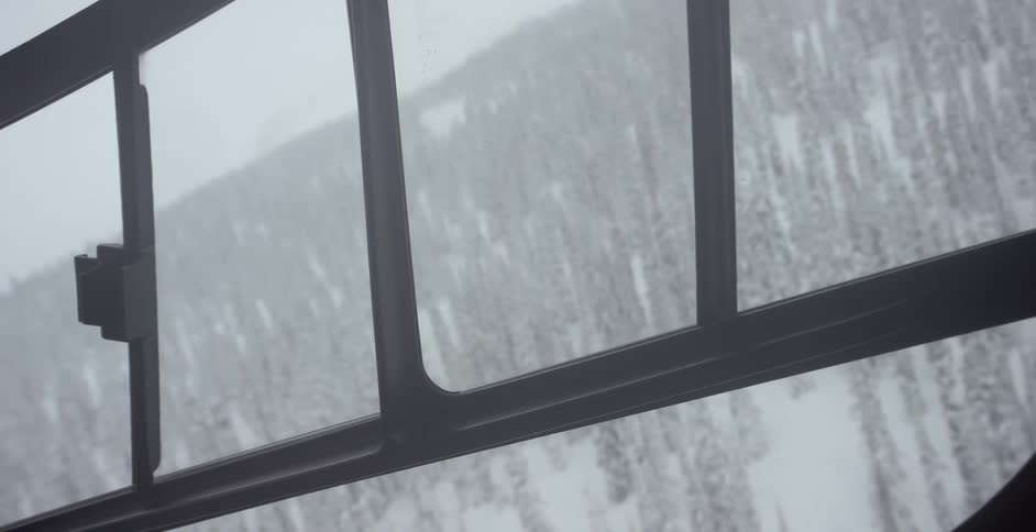 A helicopter flies over a snowy mountain forest