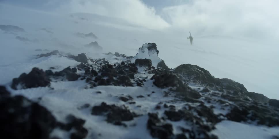 The wind howls as a skier climbs in the background