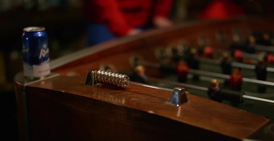 A can of beer rests on a foosball table in a bar