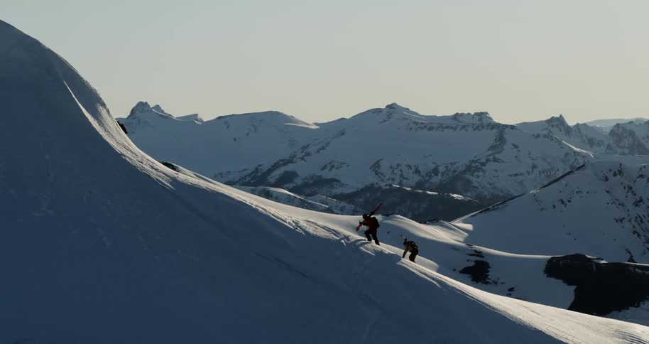 Aerial as two skiers climb a steep mountain slope