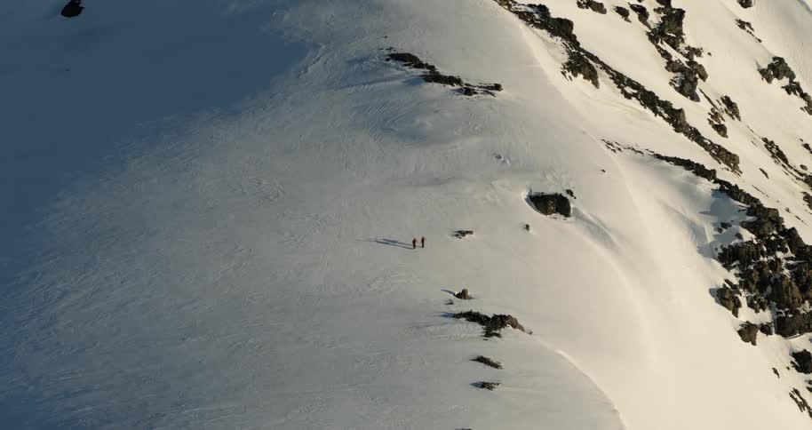 Aerial of two people moving up a massive mountain