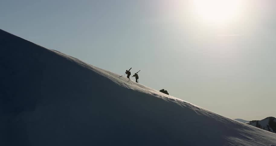 Aerial of two skiers hiking up a snowy mountain