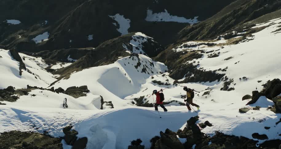 Aerial flyover of two people hiking a sheer mountain ridge