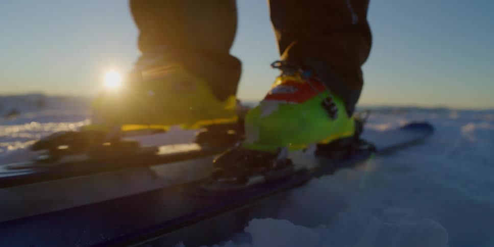 A skier's skis push along the snow at sunrise
