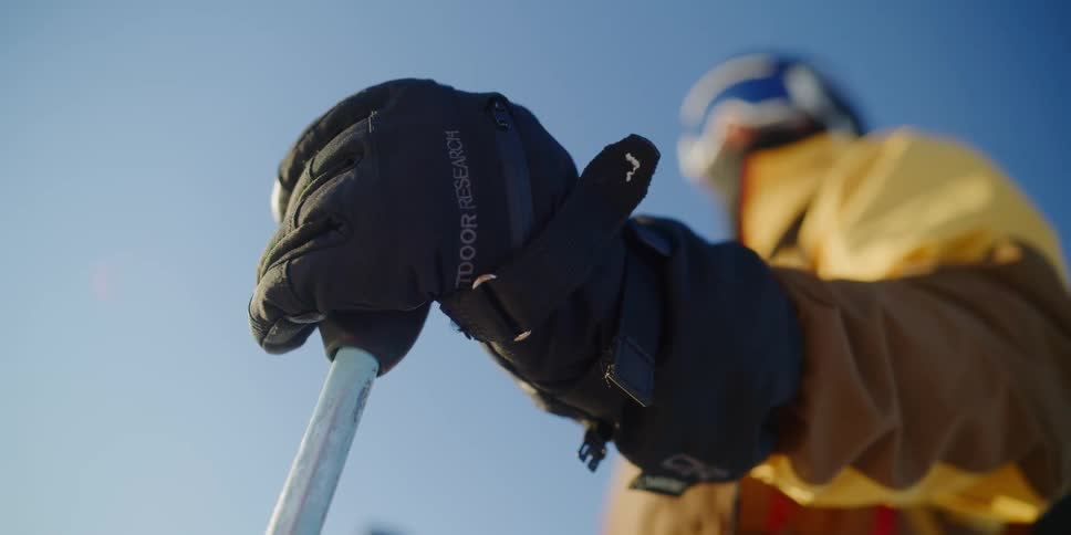 A skier stands outside, close up on ski pole