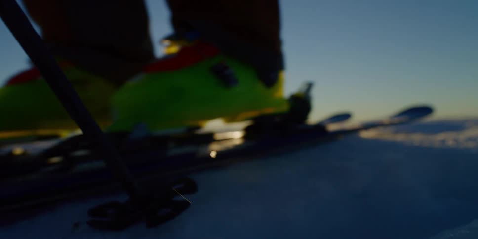 Close up of a skier pushing themselves with their poles, at sunset