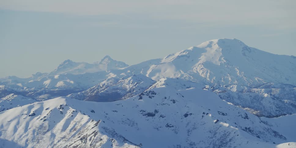 A snow covered mountain vista during the day