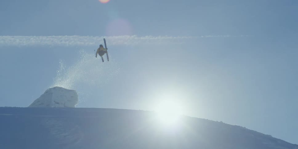 A skier jumps a snow ramp on the top of a mountain