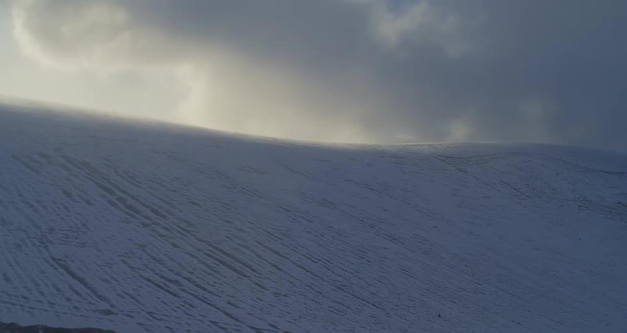 Surreal aerial push towards a flowing snowy landscape at sunset