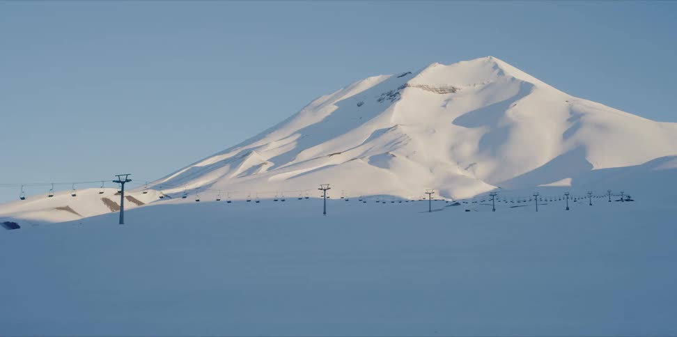 Large snow covered mountain with ski lift in distance