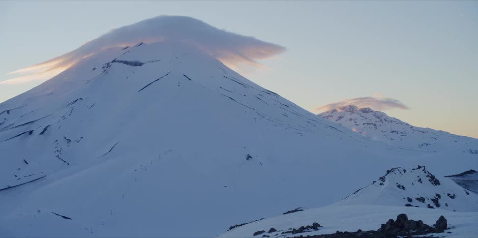 Clouds billow on a volcano peak at sunset