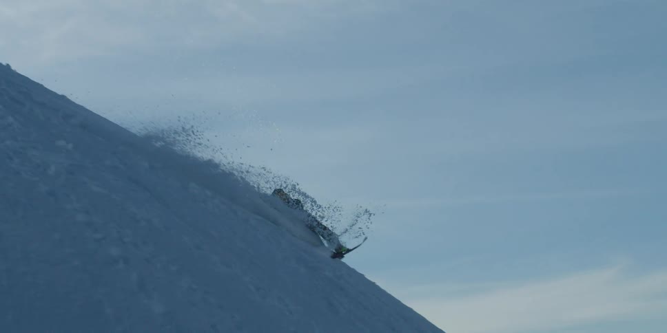 A skier performs a jump and falls down the slope of a snow covered mountain