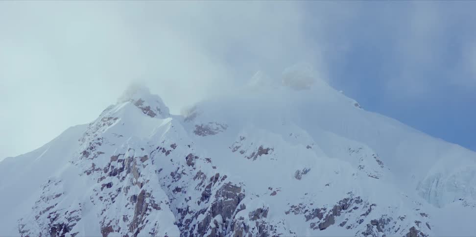 Snow blows off the top of a snow covered mountain during the winter