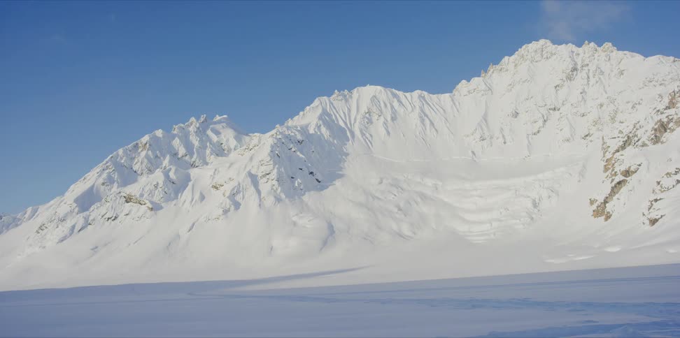 Timelapse of clouds over a snowy mountain on a blue day