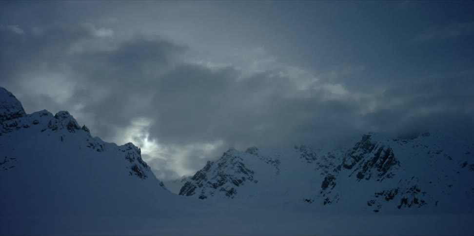 Clouds roll over the snow covered peaks as the sun sets timelapse