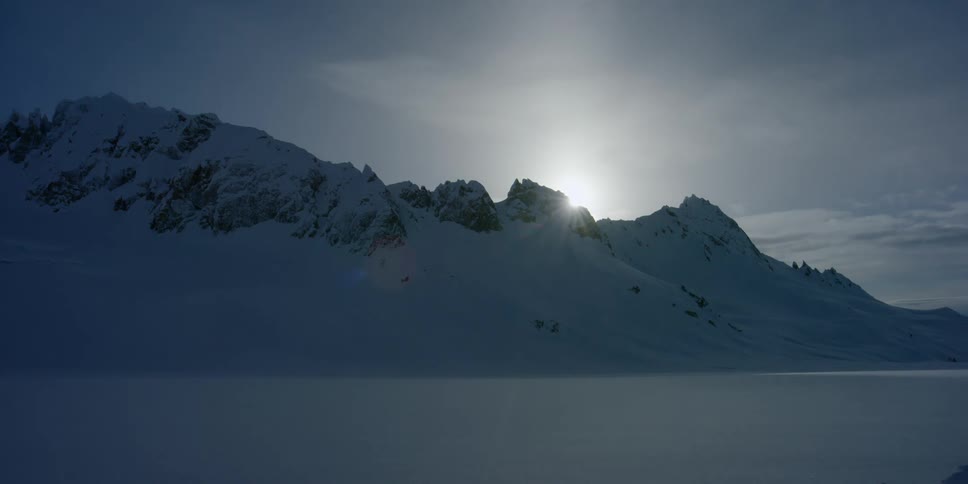 The sun rises over a snowy mountain in the wilderness timelapse