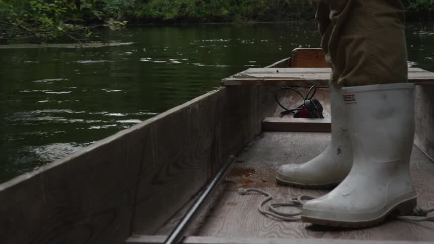 A person is standing in a small boat rowing it