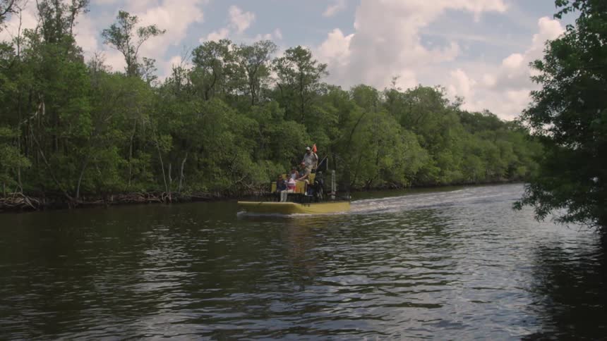People travelling down a river on an airboat
