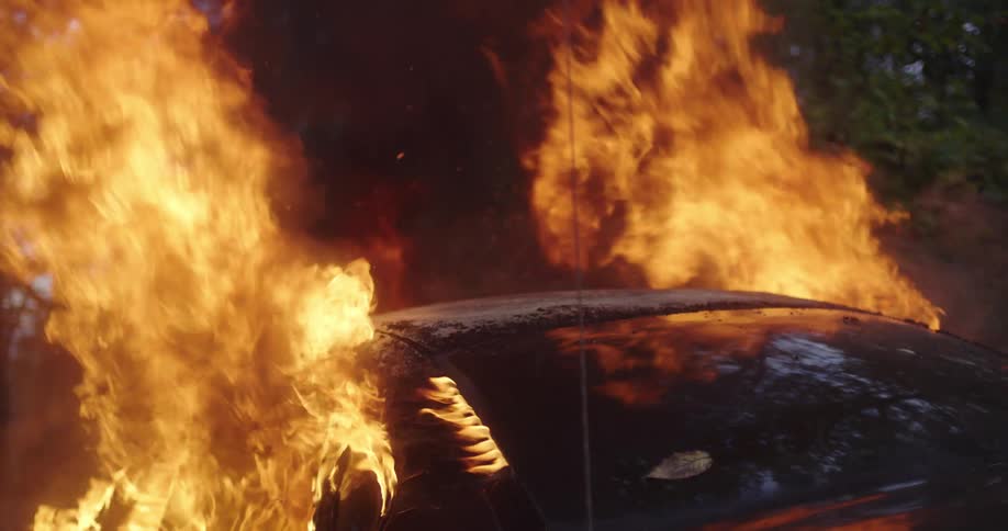 Car in fire parked outdoors with flames coming out of the windows