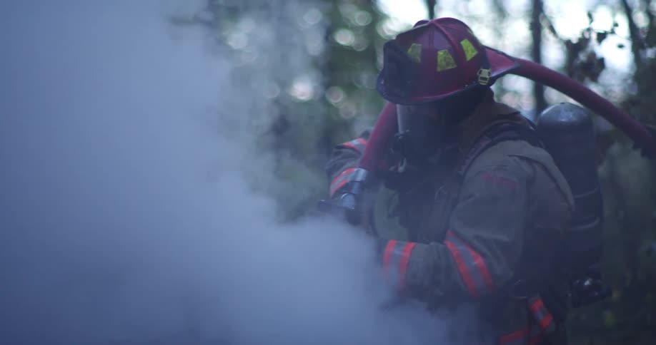 A firefighter using a hose on a smoking car