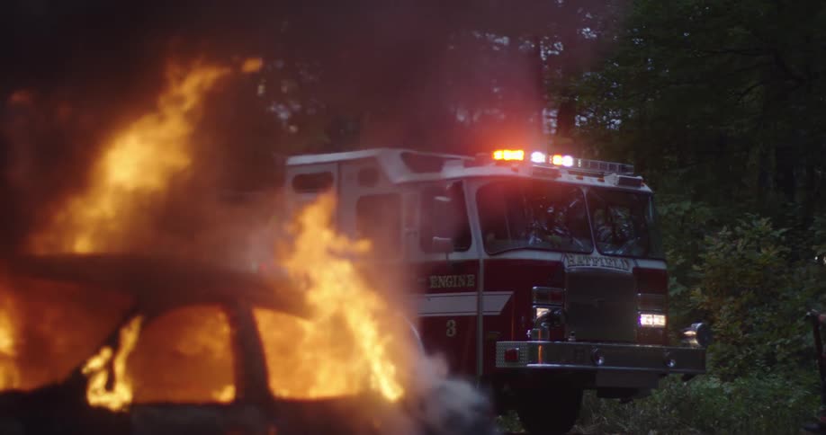A fire truck arrives to a car burning in the woods