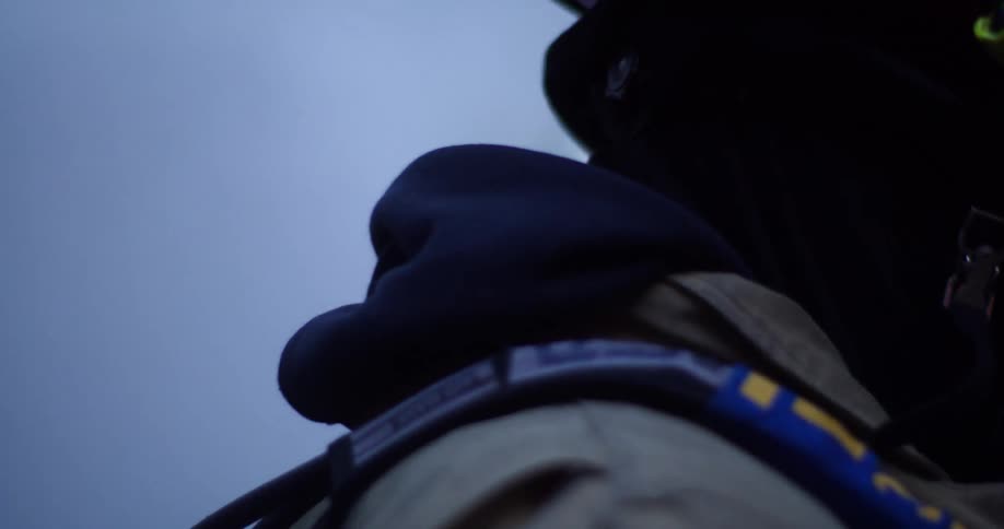 A firefighter with a respirator walking with trees and smoke in the background