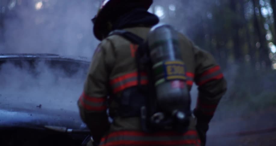 A firefighter is putting out a burning vehicle