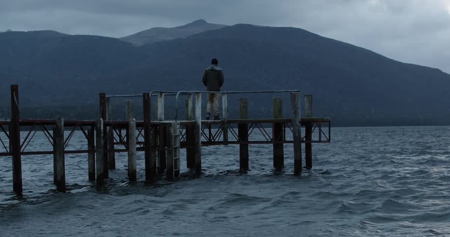 A man walks out on a dock on a body of water