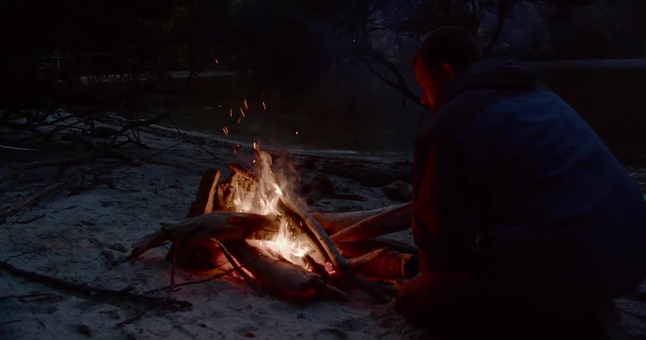 A man builds a fire on the snow covered ground