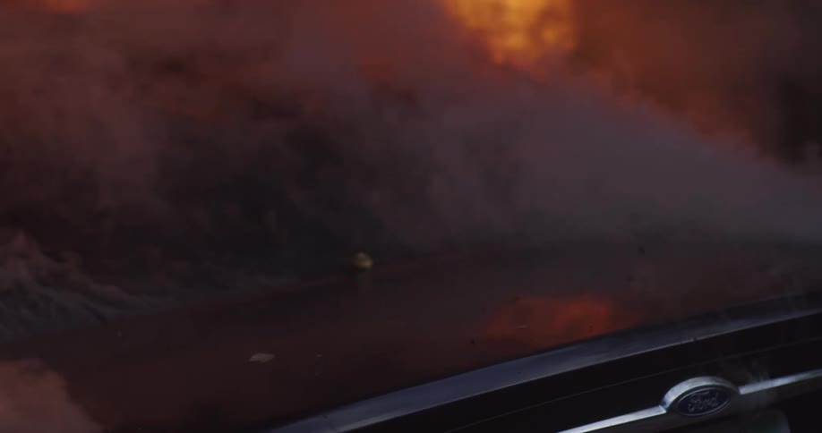 Car on fire parked outdoors with flames and smoke coming out the windows