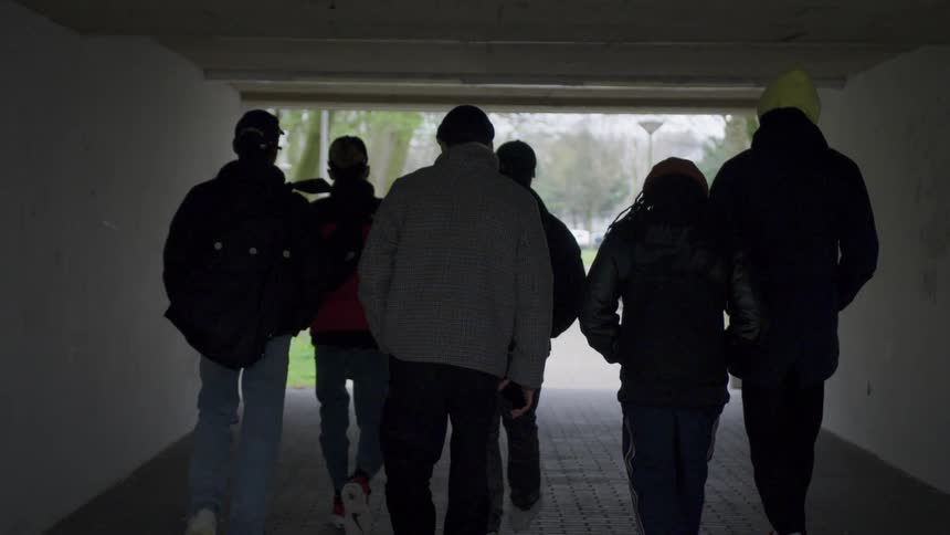 A group of young men walk through a tunnel