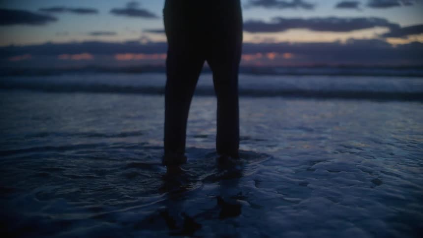 A person walks through the tide at a beach