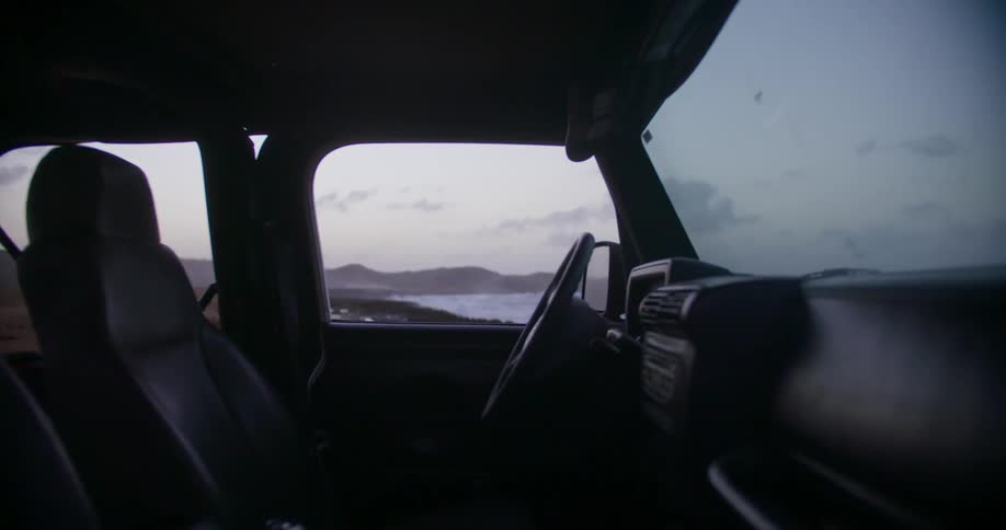 A car is parked on the shore near the ocean