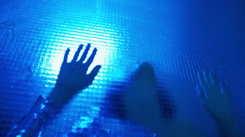 A dancer runs her hands down a pane of glass