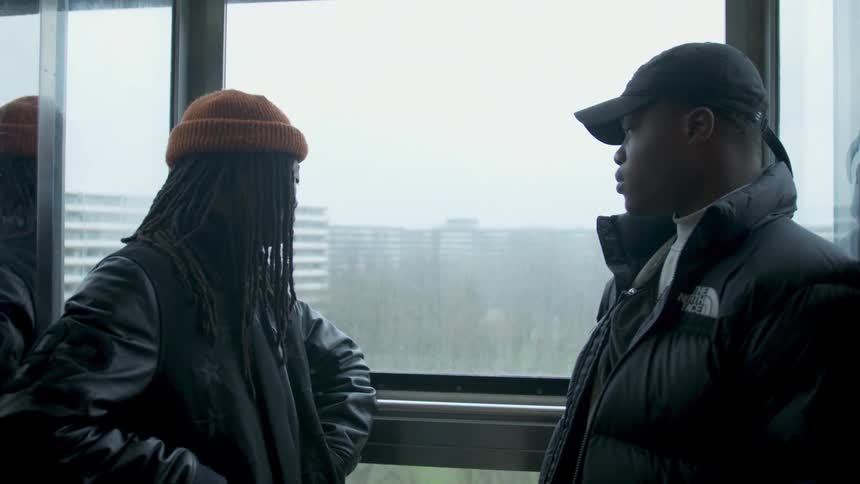Black young men riding elevator with glass windows