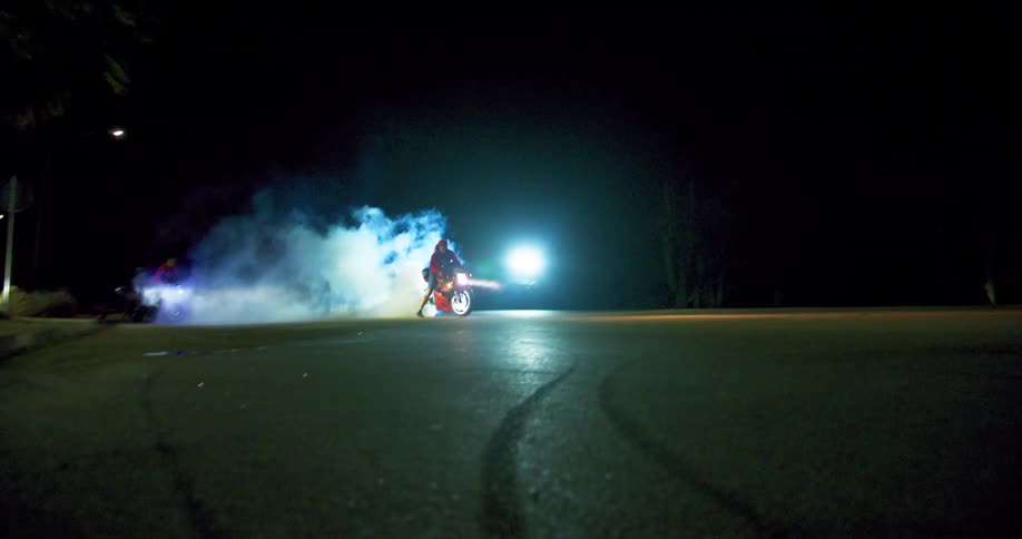 Motorcycle burning rubber on the tarmac at night