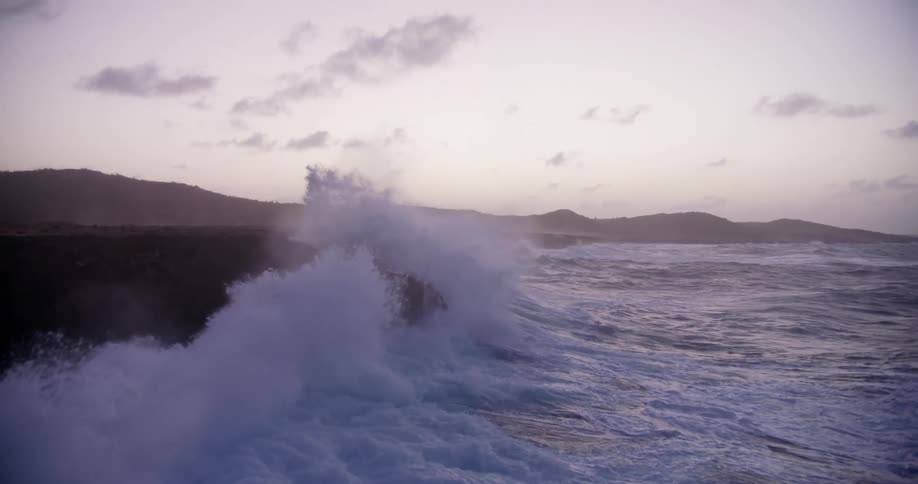 Waves crashing against a rocky coastline causing it to spray upwards