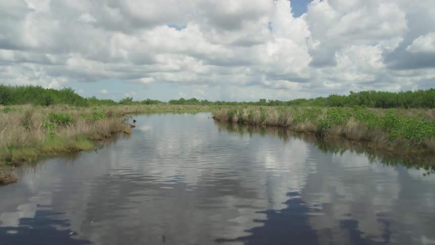 A river reflects a cloudy sky