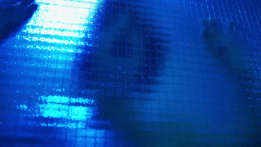 A woman dances behind glass